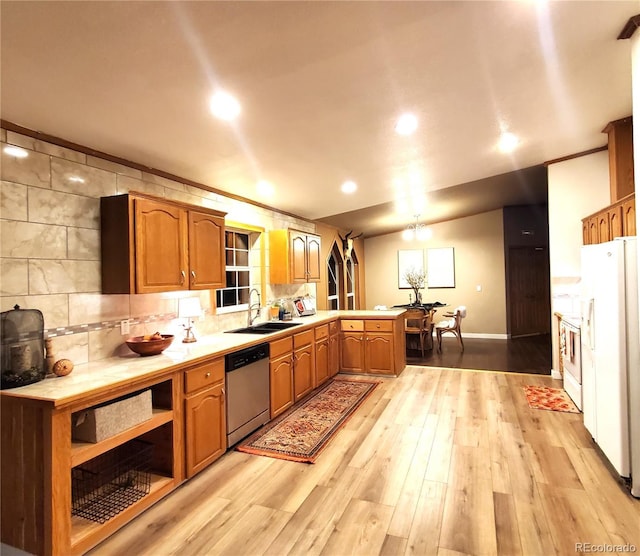 kitchen featuring white appliances, sink, decorative backsplash, light wood-type flooring, and kitchen peninsula