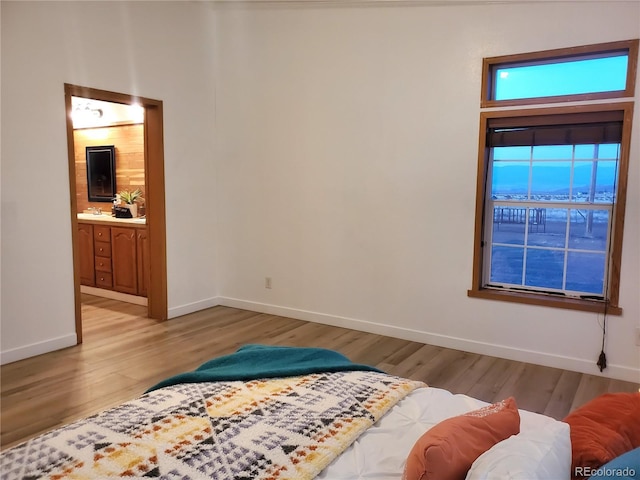 bedroom featuring light hardwood / wood-style floors, sink, and connected bathroom