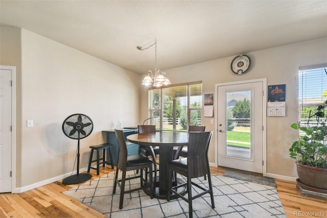 dining area with light wood-type flooring and a chandelier