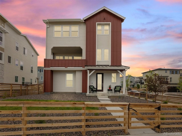 view of front facade featuring a standing seam roof, a porch, board and batten siding, and a fenced front yard