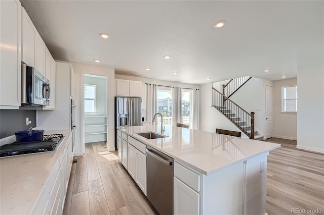 kitchen with a sink, white cabinetry, recessed lighting, stainless steel appliances, and light wood-style floors