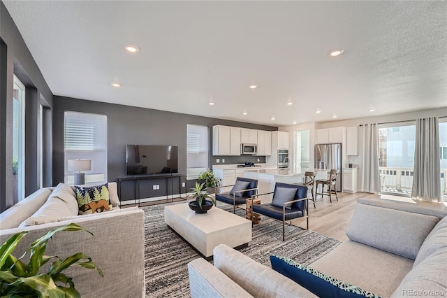 living area with recessed lighting, a textured ceiling, and light wood-style flooring