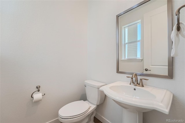 half bathroom featuring a sink, baseboards, and toilet