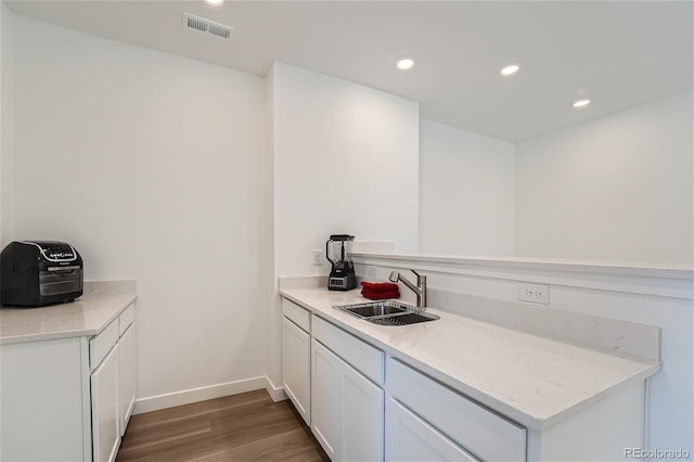 kitchen with visible vents, recessed lighting, a peninsula, wood finished floors, and a sink