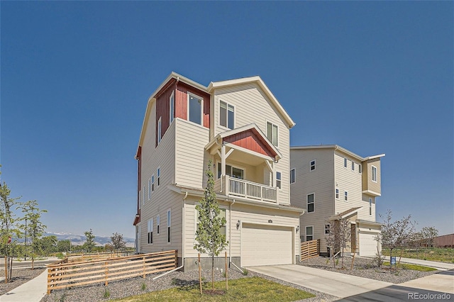 view of front facade featuring a balcony, an attached garage, fence, and driveway