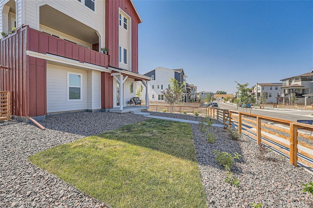 view of yard with a balcony, fence, and a residential view