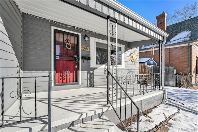 snow covered property entrance featuring a porch