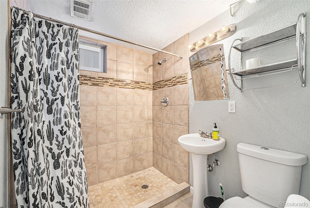 bathroom featuring sink, toilet, a shower with shower curtain, and a textured ceiling