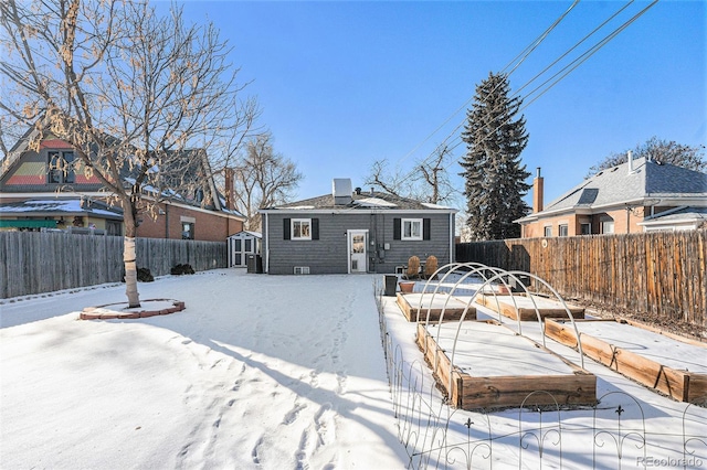 snow covered house with central AC unit and an outdoor structure