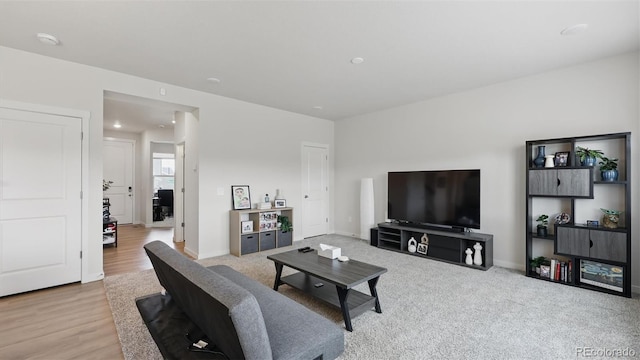 living area featuring baseboards and light wood finished floors