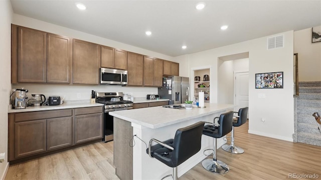 kitchen featuring stainless steel appliances, a breakfast bar area, visible vents, light countertops, and light wood-style floors