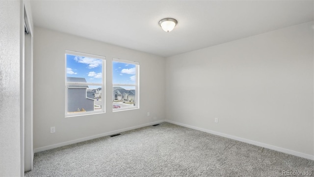 spare room featuring baseboards, visible vents, and carpet floors