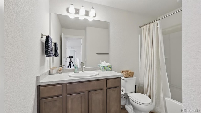 bathroom with toilet, shower / bath combo, vanity, and a textured wall
