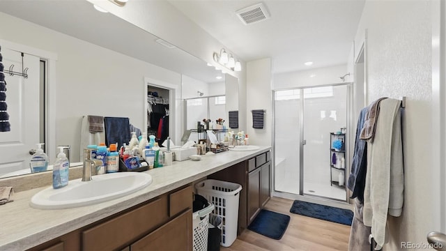 bathroom with double vanity, visible vents, a shower stall, and a sink