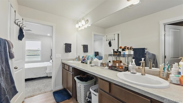 ensuite bathroom featuring a sink, double vanity, ensuite bath, and wood finished floors