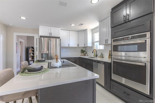5195 Allison St, Arvada, CO 80002 - kitchen featuring appliances with stainless steel finishes, a kitchen island, a kitchen bar, recessed lighting, and decorative backsplash