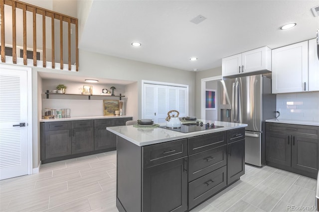 5195 Allison St, Arvada, CO 80002 - kitchen featuring stainless steel refrigerator with ice dispenser, black electric cooktop, white cabinetry, decorative backsplash, and a center island