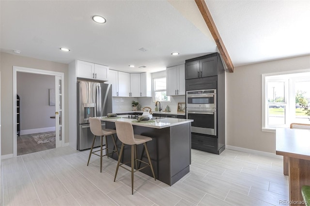 5195 Allison St, Arvada, CO 80002 - kitchen with appliances with stainless steel finishes, a kitchen breakfast bar, light countertops, a center island, and recessed lighting