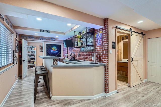 23882 E Alabama Dr, Aurora, CO 80018 - kitchen featuring a barn door, light wood-style floors, baseboards, a sink, and a peninsula