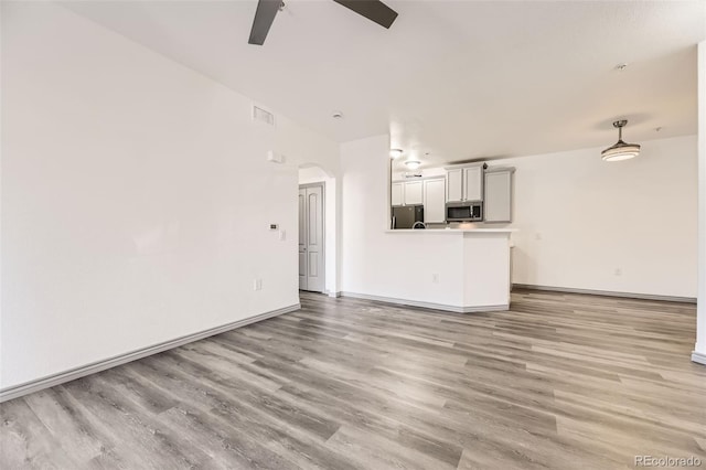 18657 Stroh Rd Unit 4103, Parker, CO 80134 - unfurnished living room with light wood-type flooring, a ceiling fan, arched walkways, and baseboards
