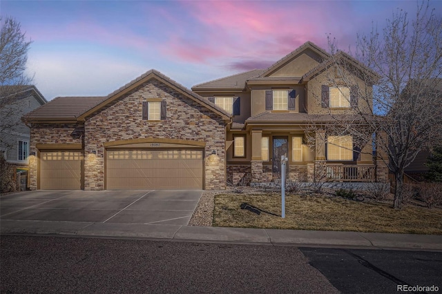 view of front of property with a garage, concrete driveway, stone siding, and stucco siding