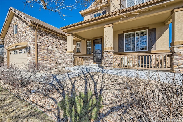 view of front facade with a garage, stone siding, covered porch, and stucco siding