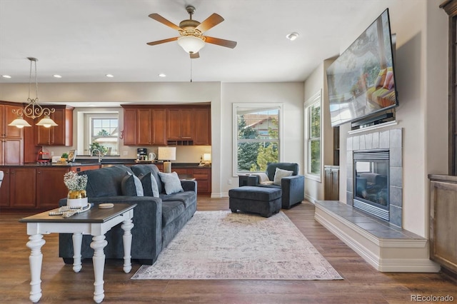 living room with dark wood-type flooring, ceiling fan, and a fireplace