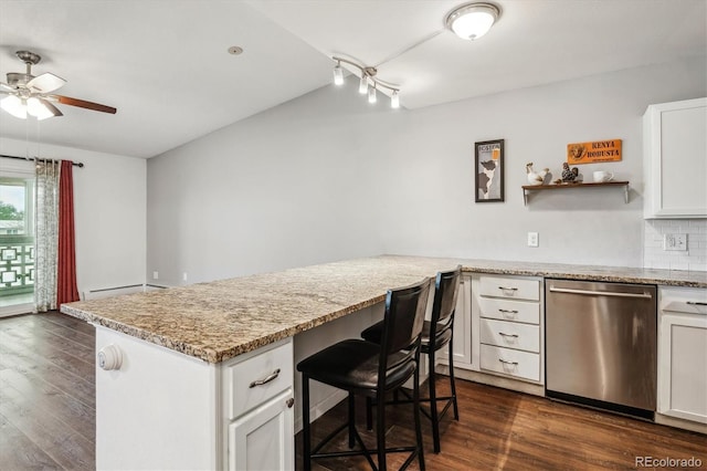 kitchen featuring dishwasher, ceiling fan, a breakfast bar area, and dark wood finished floors