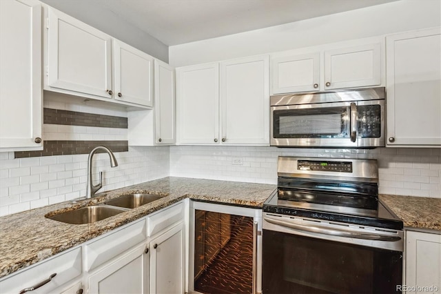 kitchen with stainless steel appliances, a sink, wine cooler, and white cabinetry