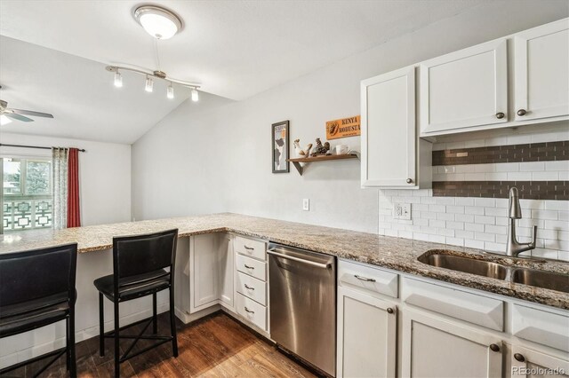 kitchen with stainless steel dishwasher, a sink, decorative backsplash, light stone countertops, and dark wood-style floors