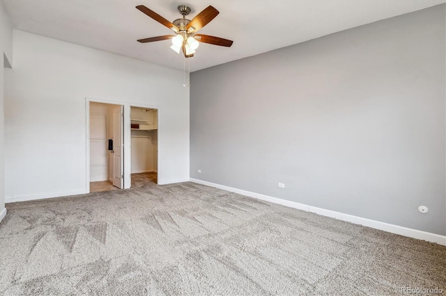 unfurnished bedroom featuring carpet, baseboards, a spacious closet, and ceiling fan