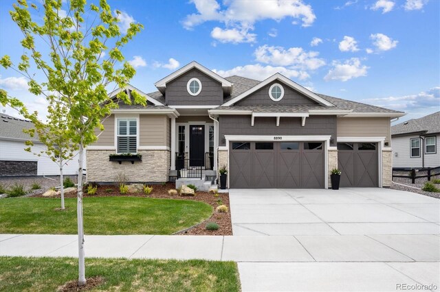 8890 S Quatar Ct, Aurora, CO 80016 - view of front of house featuring an attached garage, stone siding, driveway, and a front lawn