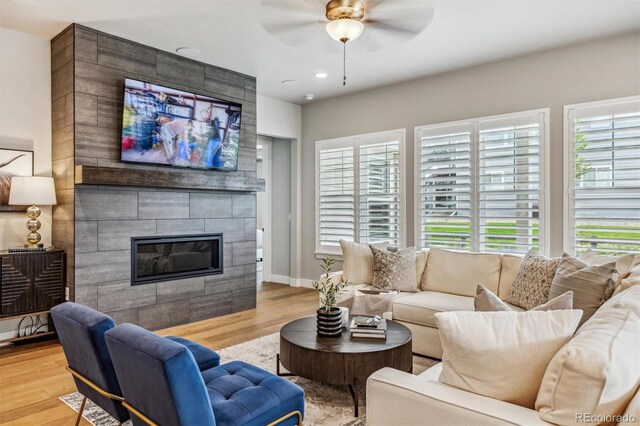 8890 S Quatar Ct, Aurora, CO 80016 - living room featuring a tile fireplace, a ceiling fan, wood finished floors, and baseboards