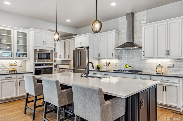 8890 S Quatar Ct, Aurora, CO 80016 - kitchen with wall chimney exhaust hood, stainless steel appliances, a sink, white cabinetry, and recessed lighting