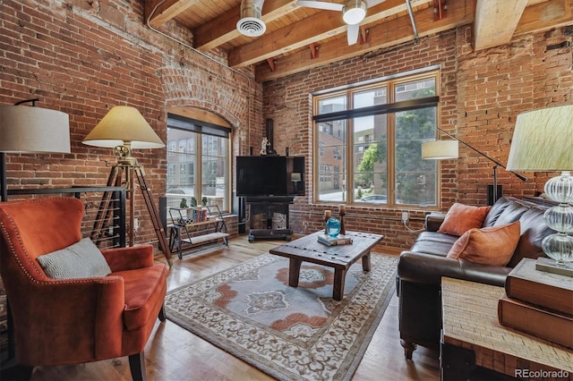 living room with brick wall, wood-type flooring, and a healthy amount of sunlight