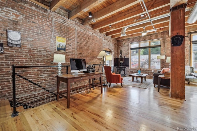 home office featuring wood ceiling, beamed ceiling, brick wall, and light hardwood / wood-style flooring