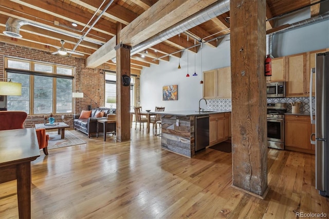 kitchen featuring appliances with stainless steel finishes, sink, brick wall, light hardwood / wood-style floors, and decorative backsplash