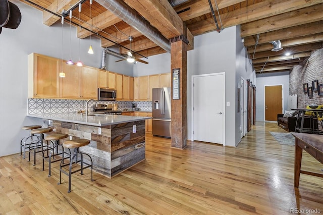 kitchen with wood ceiling, a towering ceiling, beam ceiling, and stainless steel appliances