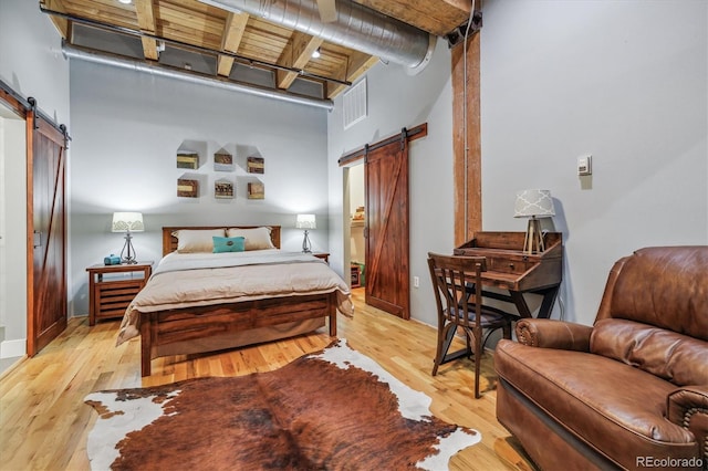 bedroom with a barn door and light wood-type flooring