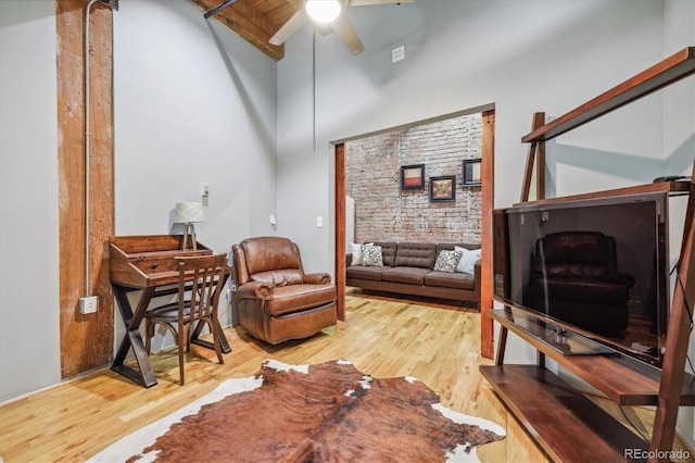 living area featuring hardwood / wood-style flooring, ceiling fan, high vaulted ceiling, and beamed ceiling