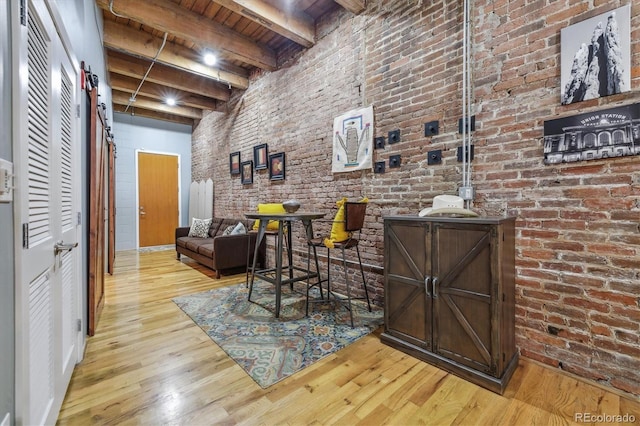 bar with wood ceiling, beamed ceiling, brick wall, and light hardwood / wood-style flooring