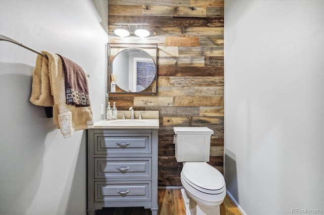 bathroom featuring vanity, toilet, wooden walls, and hardwood / wood-style floors