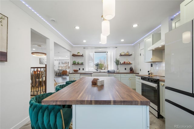 kitchen featuring white cabinets, a center island, butcher block counters, backsplash, and oven