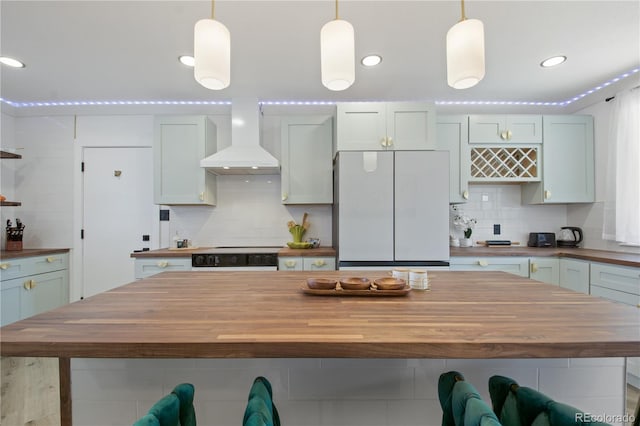 kitchen with white fridge, custom exhaust hood, pendant lighting, and butcher block counters