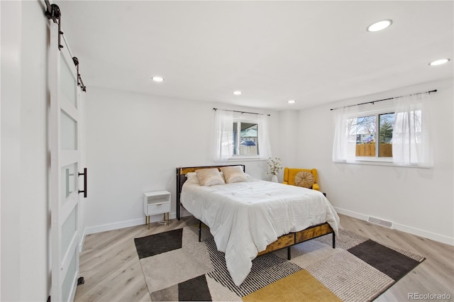 bedroom with light hardwood / wood-style floors and multiple windows