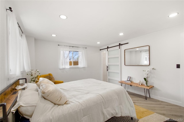 bedroom with light hardwood / wood-style flooring and a barn door