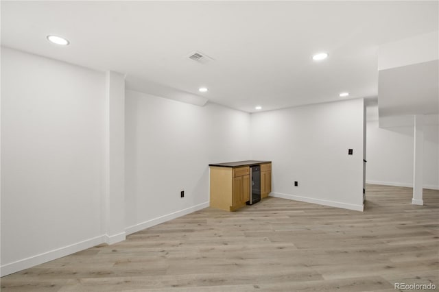 basement featuring light hardwood / wood-style floors and beverage cooler