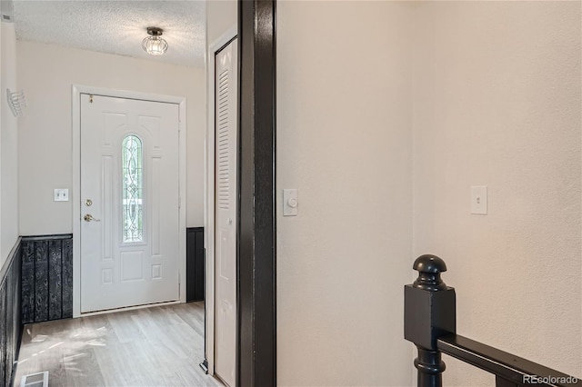 foyer entrance featuring a textured ceiling and light hardwood / wood-style flooring