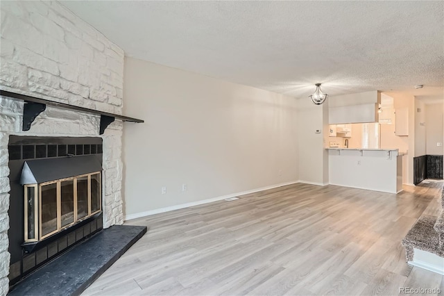 unfurnished living room with a textured ceiling, a fireplace, and light hardwood / wood-style floors