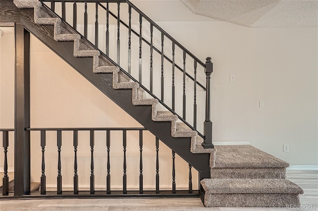 staircase featuring hardwood / wood-style floors and a textured ceiling